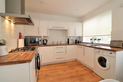 a kitchen with white cabinets and a washer and dryer at Signature - Gordon House in Glasgow