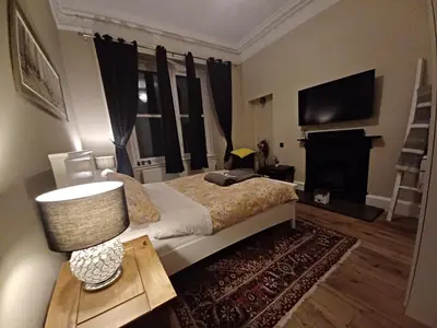 a bedroom with a bed with a lamp and a television at Murrayfield Spacious 2-bedroom apartment in Edinburgh