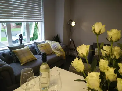 a living room with a bottle of wine and flowers on a table at Boutique Coastal appt nr Edinburgh in Saint Davids