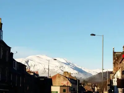 a snow covered mountain in a city with buildings at The old post office Callander holiday let in Callander