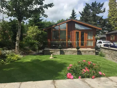 a house with a yard with a green lawn at Otter Lodge Auchterarder in Auchterarder