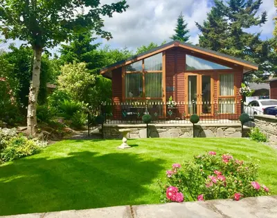 a house with a green yard with a small yard sidx sidx sidx at Otter Lodge Auchterarder in Auchterarder