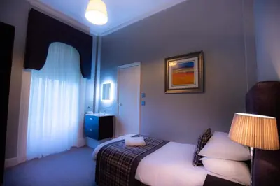 a bedroom with a bed with a lamp and a window at The Georgian hotel in Coatbridge
