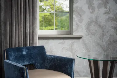 a blue chair and a glass table and a window at Dalmeny Park House Hotel in Barrhead