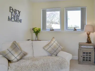 a living room with a white couch and two windows at Blueacres in Skirling
