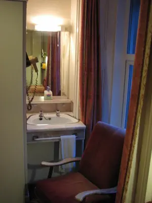 a bathroom with a chair and a sink and a mirror at Lancaster Hotel in Oban