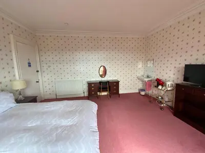 a bedroom with a white bed and a television at Dunrigh Guest House in Oban