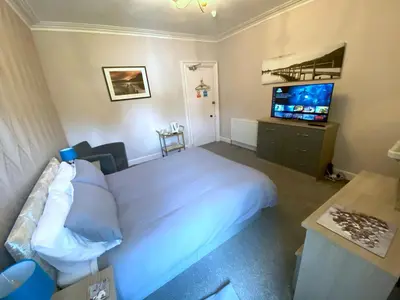 a bedroom with a white bed and a television at Dunrigh Guest House in Oban