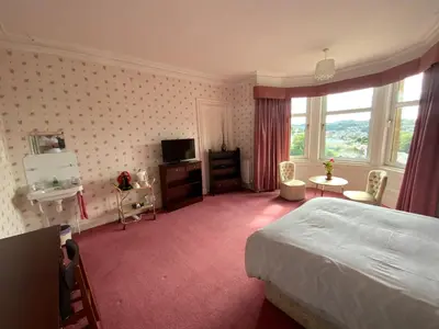 a hotel room with a bed and a tv and window at Dunrigh Guest House in Oban