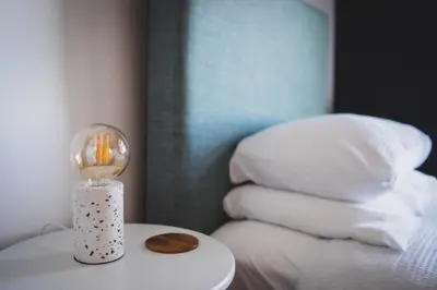 a candle on a table next to a bed with pillows at Heatherfield House in Oban