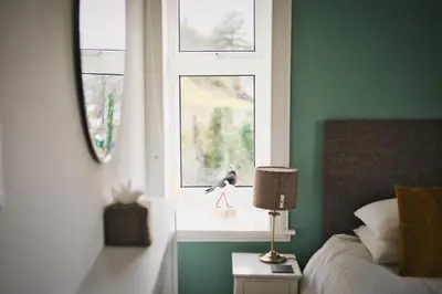 a bedroom with a window with a bird on a table at Heatherfield House in Oban