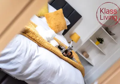 a bedroom with a bed with white sheets and yellow pillows at Albion Apartment by Klass Living Coatbridge in Coatbridge