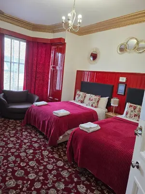a bedroom with two beds with red sheets and a couch at The Residence - NO 57 in Edinburgh