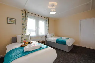 a room with two beds and a window in it at PREMIER - Garfield House in Bellshill
