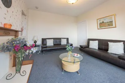 a living room with couches and a table and flowers at PREMIER - Garfield House in Bellshill