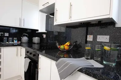 a kitchen with white cabinets and a bowl of fruit on the counter at PREMIER - Garfield House in Bellshill