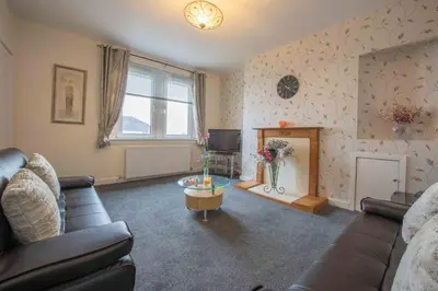 a living room with a couch and a fireplace at PREMIER - Garfield House in Bellshill