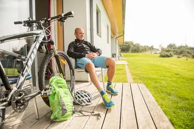 a man sitting on a porch next to a bike at Portavadie Loch Fyne Scotland in Portavadie