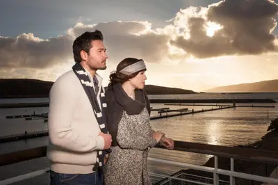 a man and a woman standing on a pier with the sunset at Portavadie Loch Fyne Scotland in Portavadie