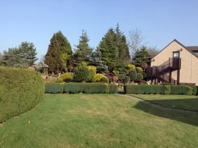 a yard with a house and some bushes and a house at Ashcroft Farmhouse in East Calder