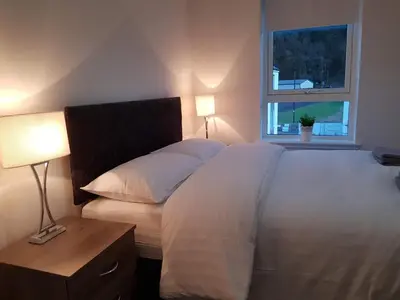 a bedroom with a large white bed and a window at 3 Royal View Apartments in Stirling