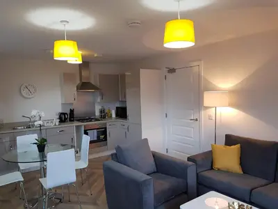 a living room with two couches and a table and a kitchen at 3 Royal View Apartments in Stirling
