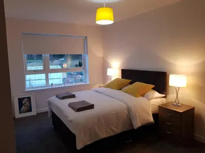 a bedroom with a large bed with two towels on it at 5 Royal View Apartments in Stirling
