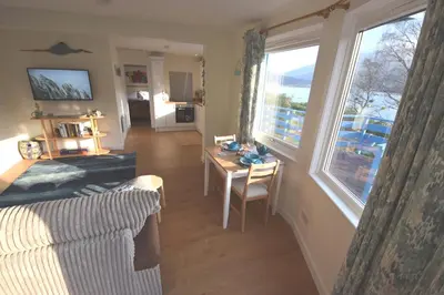 a living room with a couch and a table and a window at Byron Cottage overlooking Loch Goil in Lochgoilhead