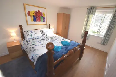 a bedroom with a bed with a blue comforter at Byron Cottage overlooking Loch Goil in Lochgoilhead
