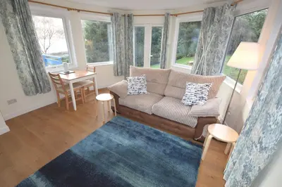 a living room with a couch and a table and windows at Byron Cottage overlooking Loch Goil in Lochgoilhead