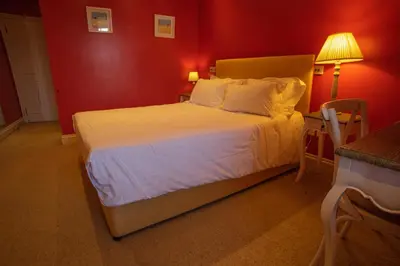a bedroom with a white bed with a red wall at Buccleuch and Queensberry Arms Hotel in Thornhill