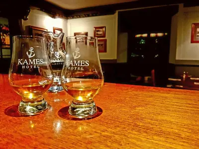 three wine glasses sitting on top of a wooden table at Kames Hotel in Tighnabruaich