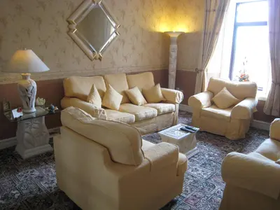 a living room with a couch and two chairs at Herdshill Guest House in Wishaw