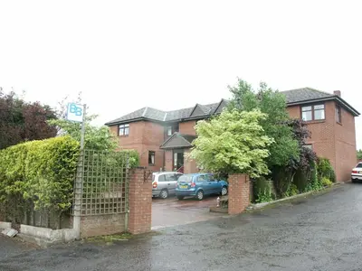 a house with cars parked in a parking lot at Herdshill Guest House in Wishaw