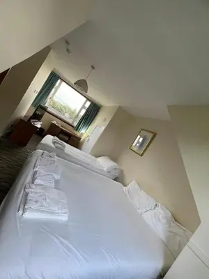 a large white bed in a room with a window at Lochway Hotel in Dumbarton