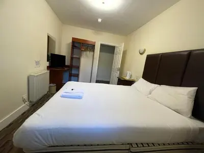 a bedroom with a large white bed with a black headboard at Lochway Hotel in Dumbarton