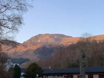 a mountain in the distance with a building in front of it at Ben Lomond Lodge in Rowardennan
