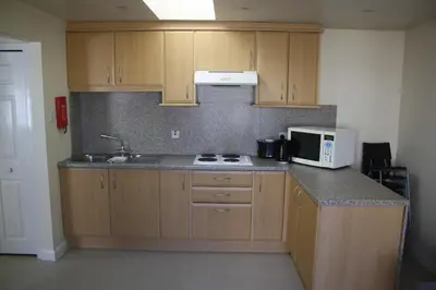 a kitchen with wooden cabinets and a sink and a microwave at Fairways Cottages in Prestwick