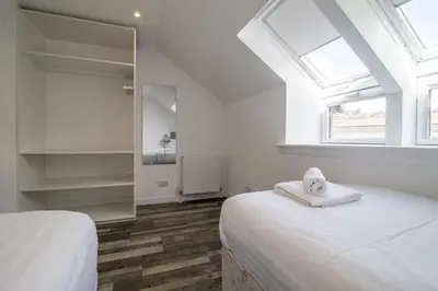 a white bedroom with a bed and a mirror at Abbey House in Paisley