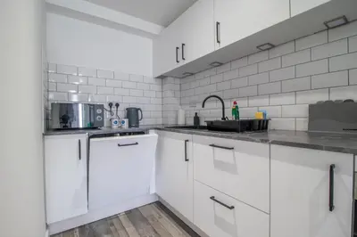 a kitchen with white cabinets and a sink at Abbey House in Paisley
