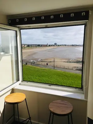 a window with two stools and a view of a beach at South Beach Apartment in Ardrossan