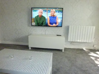 a living room with a flat screen tv on a wall at Paisley Central Apartment #4 in Paisley