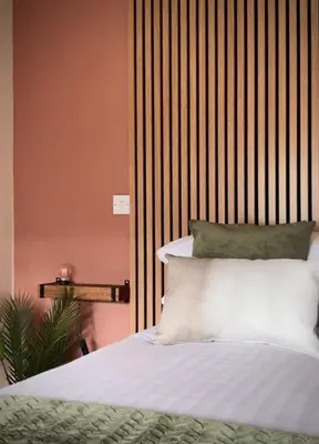 a bedroom with a bed with white sheets and green pillows at Lochside Guest House in Arrochar
