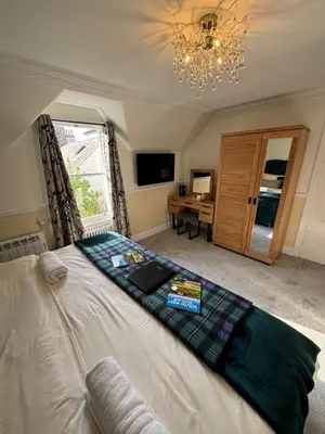 a bedroom with a bed with a desk and a window at Buchan Guest House in Moffat