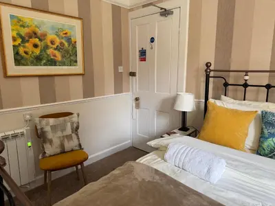 a bedroom with a bed and a chair and a painting at Buchan Guest House in Moffat