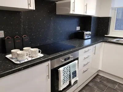 a kitchen with white cabinets and black counter tops at Carnegie Place in East Kilbride