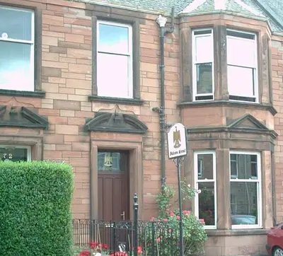 a brick house with a sign in front of it at Falcon Crest Guest House in Edinburgh