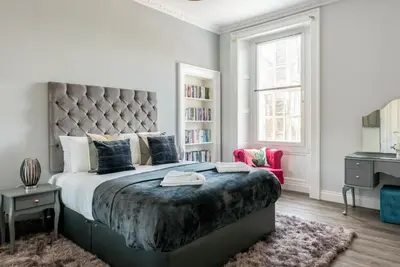 a bedroom with a large bed with a large headboard at Spacious newly refurbished central apt in Edinburgh
