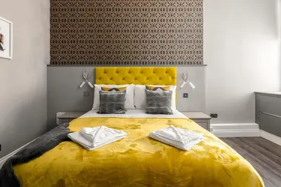 a bedroom with a large yellow bed with two pillows at Spacious newly refurbished central apt in Edinburgh