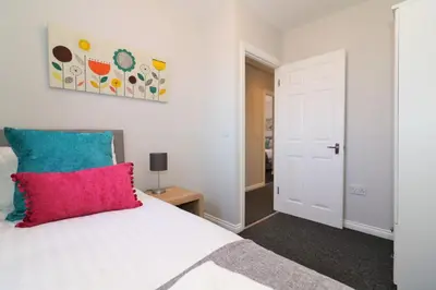 a bedroom with a white bed with a red pillow at Signature- Connelly House in Motherwell